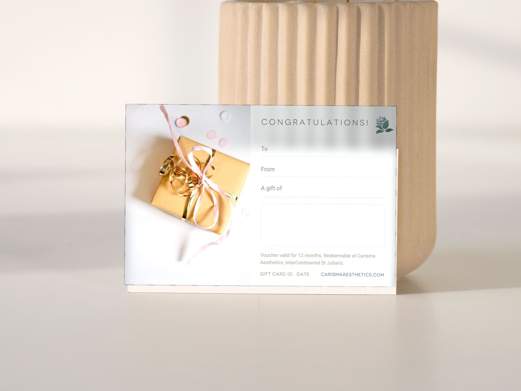 A Carisma Aesthetics congratulations gift card on white linen with an anthurium — Congratulations gift cards at Carisma Aesthetics Malta