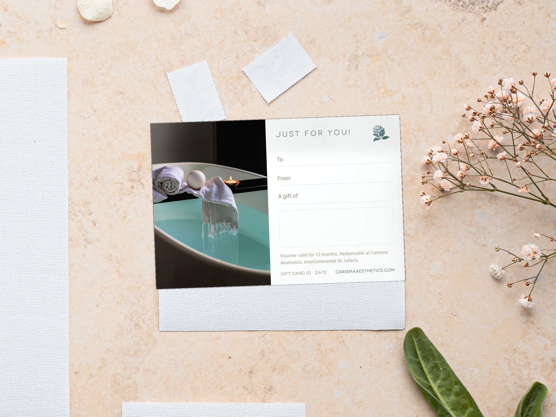A Carisma Aesthetics gift card on pale plaster with a scallop shell and a white bloom — Just For You gift cards at Carisma Aesthetics Malta