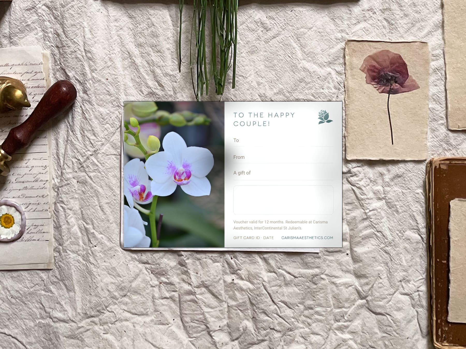 A Carisma Aesthetics gift card between dried palm fans on a pale ivory ground — Wedding & Honeymoon gift cards at Carisma Aesthetics Malta