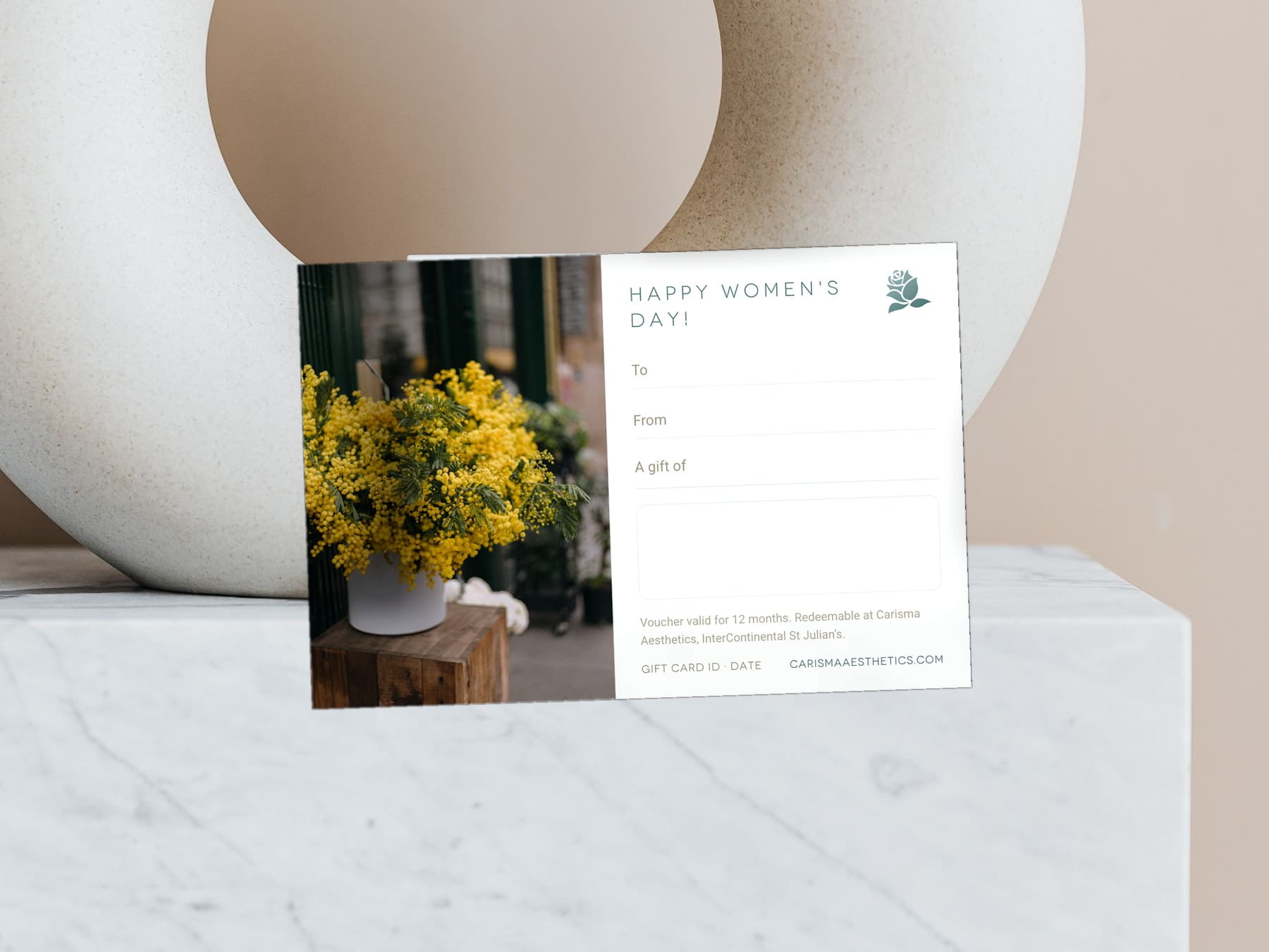 A Carisma Aesthetics Women's Day gift card with mimosa and lilac on pale stone — Women's Day gift cards at Carisma Aesthetics Malta